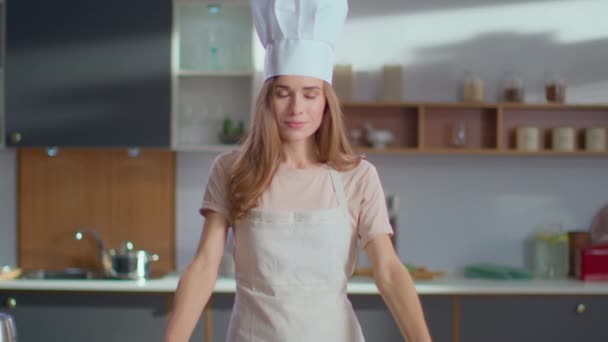 Lächelnder Koch in der Küche. Frau mit Kochmütze legt Hand an Küche - Filmmaterial, Video