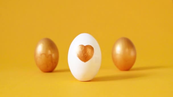 Χρυσά αυγά σε κίτρινο φόντο. Χαρούμενο Πάσχα - Πλάνα, βίντεο