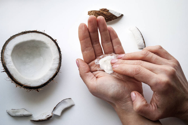 Woman smears her hands with natural cream. Female hands close-up top view. Organic cosmetics with coconut on white background top view mockup.  - Photo, Image