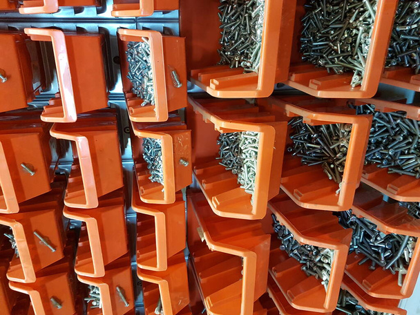 Schrauben in orangefarbenen Aufbewahrungsboxen in einer Werkstatt - Foto, Bild