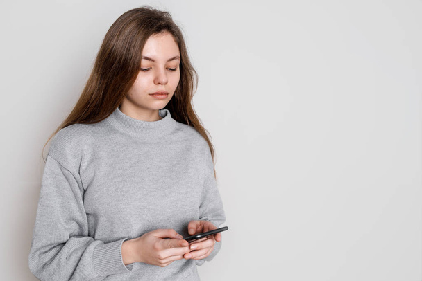 fröhliche junge Frau mit Smartphone im Studio auf weißem Hintergrund. Jahrtausendkonzept. Soziale Medien - Foto, Bild