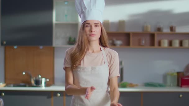 Chef em chapéu de fogão em pé no local de trabalho. Mulher piscando na câmera na cozinha
 - Filmagem, Vídeo