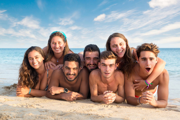 Группа счастливых молодых людей на пляже - Фото, изображение