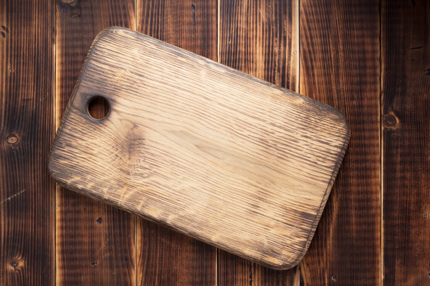 cutting board at rustic wooden plank background, top view - Foto, imagen