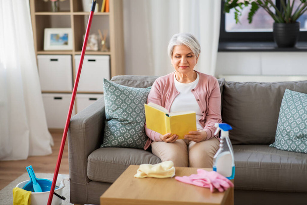 senior woman reading book after home cleaning - Photo, image