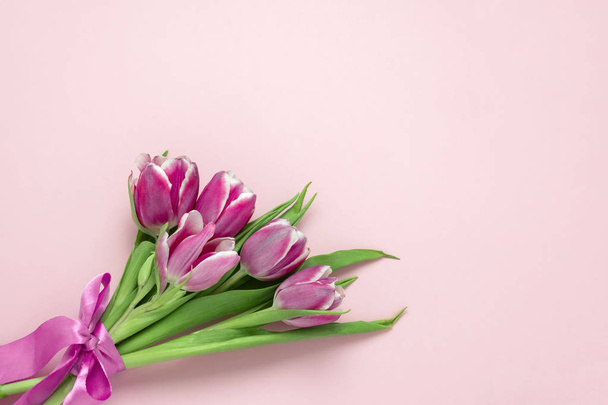 top view flat lay cute pink tulips with silk ribbon on a soft pink background with copy space, spring holidays card concept - Zdjęcie, obraz
