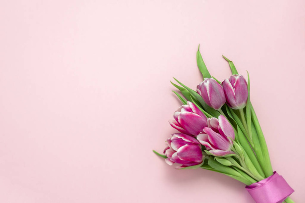 top view flat lay cute pink tulips with silk ribbon on a soft pink background with copy space, spring holidays card concept - Fotografie, Obrázek