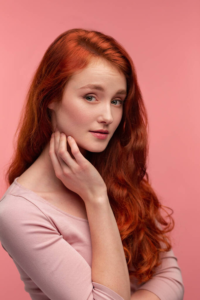 Portrait of smiling redhead girl. Perfect skin. Beautiful female model with long hair over pink background. Young cute woman with clear skin. Skincare and facial treatment concept - Fotoğraf, Görsel