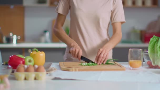 Woman cutting onions on wooden board at kitchen. Housewife preparing salad - Video, Çekim