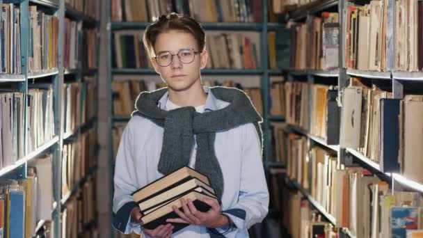Portrait of handsome teenage boy in the library - Materiał filmowy, wideo