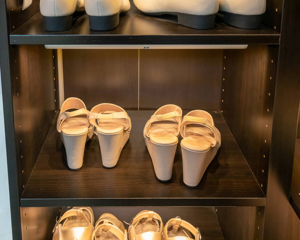 Lumière crème couleur nue dame chaussures de mode en bois sombre étagère de l'armoire
. - Photo, image