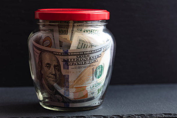 100 dollar bills in jar on black background - Fotó, kép