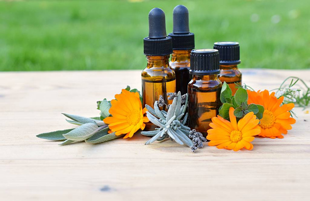 Set aus braunen Flaschen mit ätherischen und kosmetischen Ölen, frischen Kräutern und Blumen, Aromatherapie, Phytotherapie. - Foto, Bild