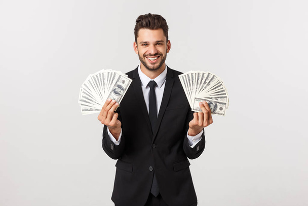 Портрет задоволеного молодого бізнесмена, який тримає купу грошових купюр, ізольованих на білому тлі
. - Фото, зображення