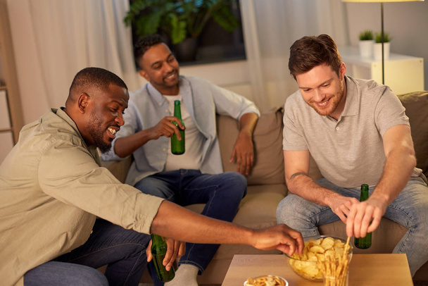 male friends drinking beer with crisps at home - Foto, Imagem