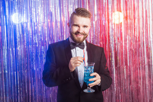 Club party and holidays concept - Portrait d'un élégant bel homme en costume cher tient cocktail bleu sur fond brillant
. - Photo, image