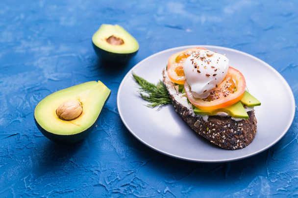 Sandwich met gerookte zalm, ei en avocado op blauwe achtergrond, bovenaanzicht. Concept voor gezonde voeding. - Foto, afbeelding