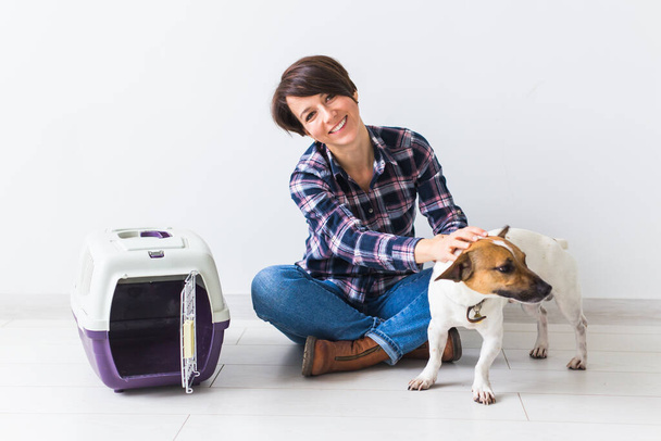 Pes nesoucí tašky a domácí mazlíček - Atraktivní veselá fena v kostkované košili drží oblíbené zvířátko. Šťastná žena se svým jack Russell teriér - Fotografie, Obrázek