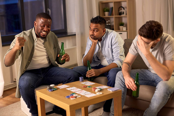male friends playing cards at home at night - Fotó, kép