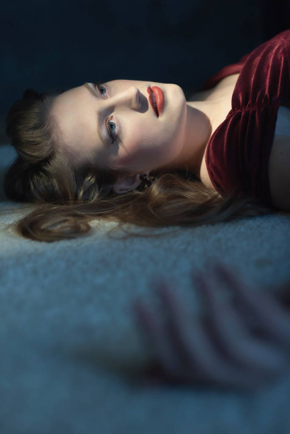 Убитая женщина в красном платье лежит на полу
. - Фото, изображение