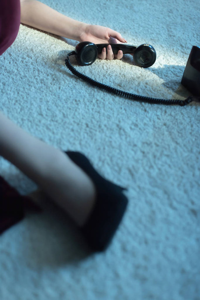 Nő telefonnal a kezében piros ruhában és fekete cipő fehér szőnyegen. - Fotó, kép