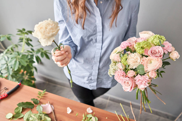 Жінка-флорист створює гарний букет у квітковому магазині. Робота в квітковому магазині. Доставка квітів
. - Фото, зображення