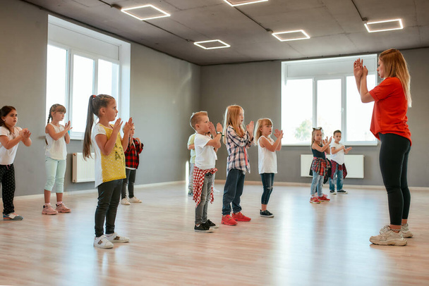 Learning a new dance. Group of little boys and girls dancing while having choreography class in the dance studio. Dance teacher and children - Zdjęcie, obraz