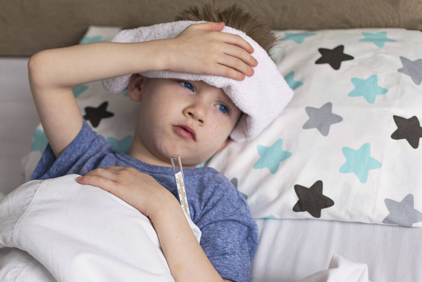 Malade enfant triste dans la température et les maux de tête se trouve dans le lit. Grippe rhume maladie virus bactérie
 - Photo, image