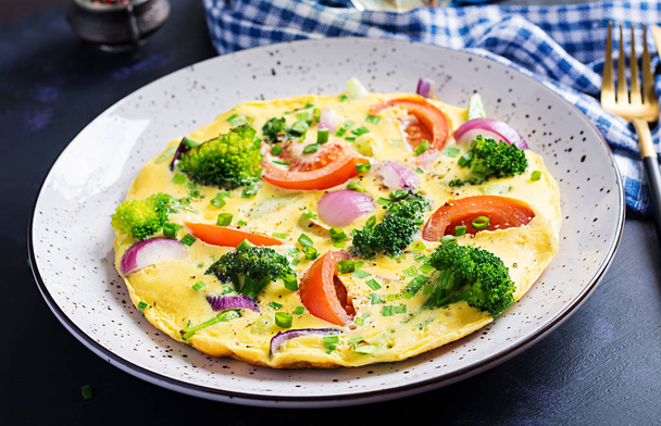 Omelette con broccoli, pomodori e cipolle rosse su tavolo scuro. Frittata italiana con verdure
. - Foto, immagini
