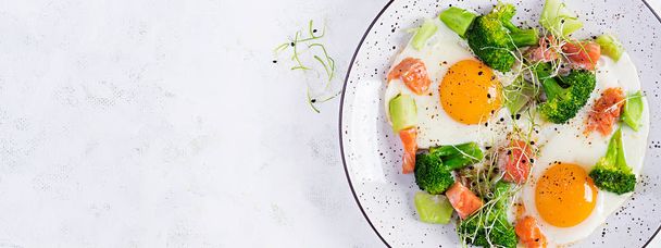 Ketogenic/paleo diet. Fried eggs, salmon, broccoli and microgreen.  Keto breakfast. Brunch.  Top view, banner - Foto, Bild