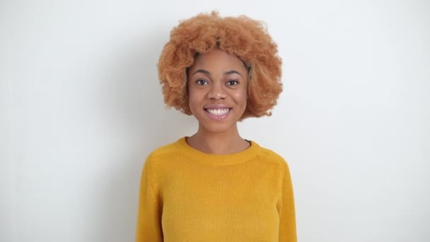 Porträt einer lächelnden afroamerikanischen jungen Frau mit lockigem Haar. Glückliches schwarzes Mädchen auf weißem Hintergrund. - Filmmaterial, Video