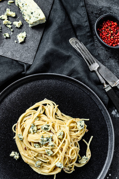Spagetti paszta krém kék sajt szósszal és dióval. Olasz házi étel. Fogantatás egy ízletes, vegetáriánus ételre. Fekete háttér. Felülnézet. - Fotó, kép
