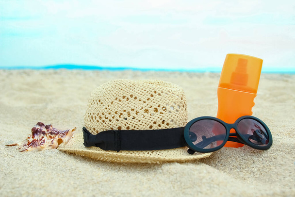 beautiful hat with glasses and cream on the sea in the sand background - Foto, Imagen