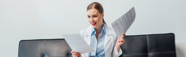 panoramic shot of happy and sexy nurse holding documents - Foto, afbeelding