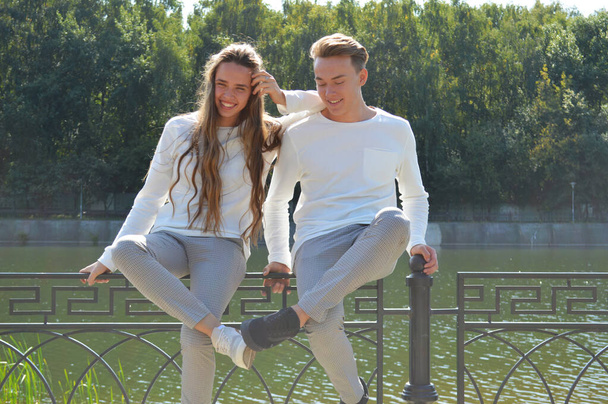Una giovane ragazza e un giovane con gli stessi vestiti su un ponte vicino all'acqua
 - Foto, immagini