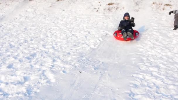 Ένα παιδί ιππεύει και παίζει σε ένα χιονισμένο βουνό. Αργή κίνηση. Χιονισμένο χειμερινό τοπίο. Υπαίθρια αθλήματα - Πλάνα, βίντεο