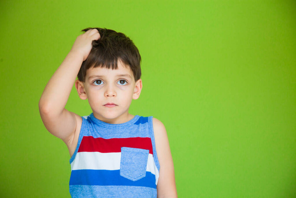 a young boy in a striped t-shirt poses on a green background - Φωτογραφία, εικόνα
