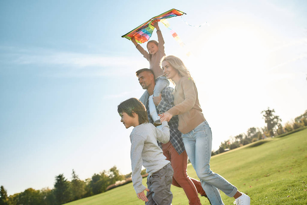 Let your children spread the wings. Happy family playing a kite. Outdoor family weekend - Fotografie, Obrázek