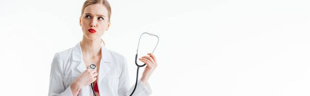 panoramic shot of sexy nurse in white coat holding stethoscope isolated on white  - Zdjęcie, obraz