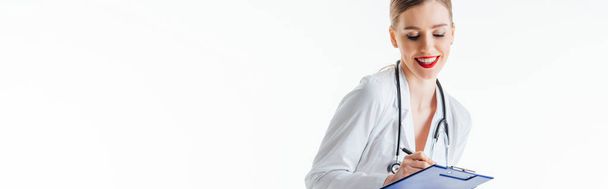 панорамний знімок щасливої і сексуальної медсестри, що пише рецепт, тримаючи буфер обміну ізольовано на білому
  - Фото, зображення