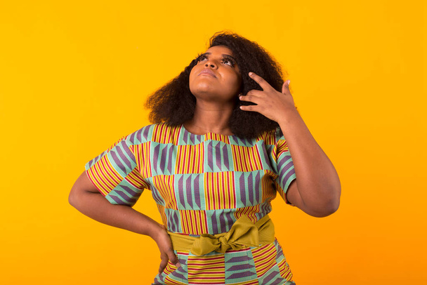 Junge schöne afrikanisch-amerikanische Mädchen mit einer Afrofrisur. Porträt auf gelbem Hintergrund. - Foto, Bild