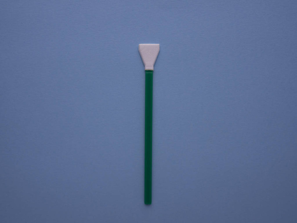 Green cleaning swab for the camera matrix isolated on blue background top view with copy space. Mop for sensor cleaning. Digital camera service. - Zdjęcie, obraz