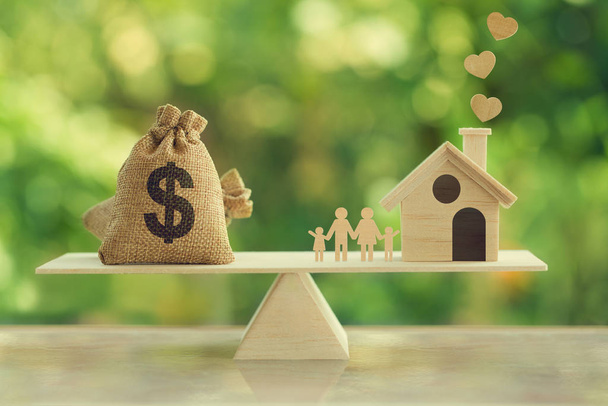 Immobilieninvestition und Hypothekenkonzept: Holzhaus, Familie und Wir-Dollar-Hessen-Taschen auf Holzwaage. Finanzmanagement der Familie für eine Residenz. - Foto, Bild