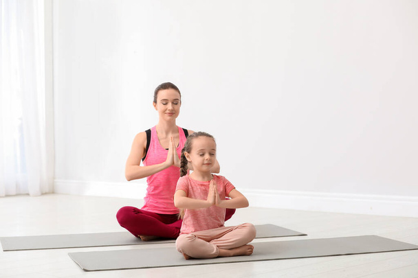 Young mother with little daughter practicing yoga at home - Zdjęcie, obraz