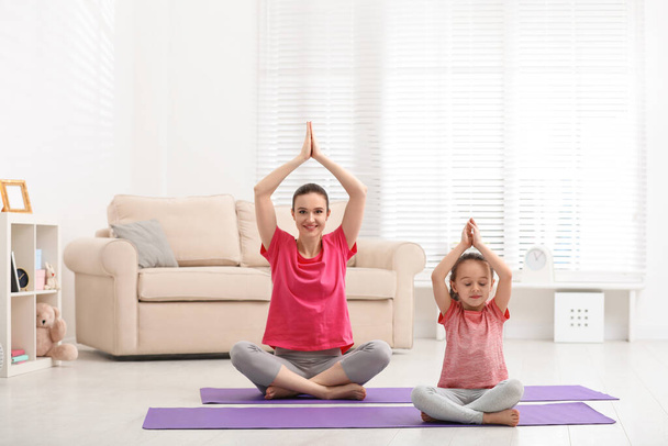 Young mother with little daughter practicing yoga at home - Foto, immagini