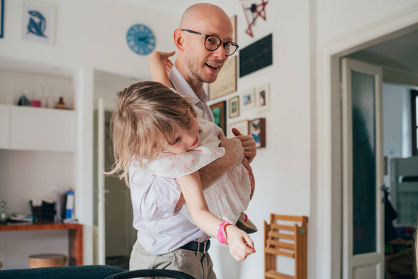 Daddy playing indoor holding her daughter - happiness, weekend activities, bonding concept - Photo, Image