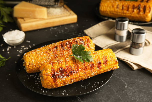 Delicious grilled corn cobs on black table - Foto, Imagem