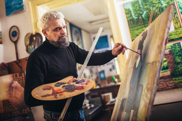 Reifer Mann malt auf Leinwand im Kunstatelier. - Foto, Bild