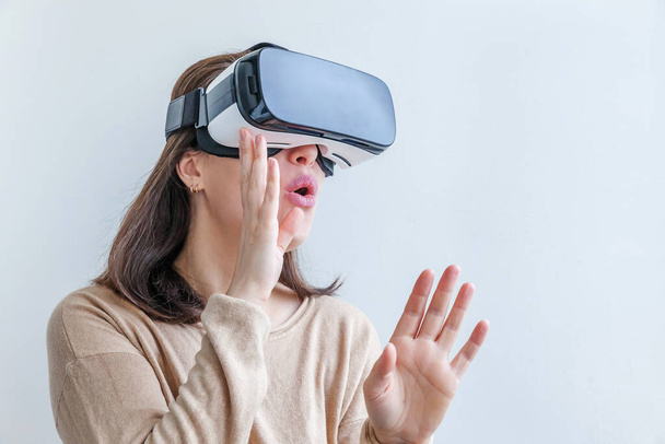 Посміхайтеся, молода жінка вдягнена за допомогою гарнітури VR окулярів на білому тлі. Використання смартфона з окулярами віртуальної реальності. Технологія, симуляція, хай-тек, концепція відеоігор
 - Фото, зображення