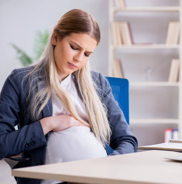 Zwangere vrouw werknemer in het kantoor - Foto, afbeelding